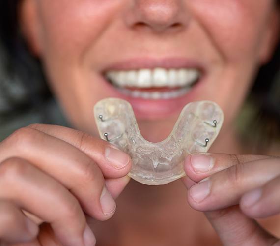 a patient holding up their nightguard for bruxism