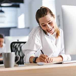 Woman smiling while working on phone in office