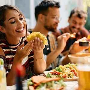 Woman smiling while eating meal with friends at restaurant