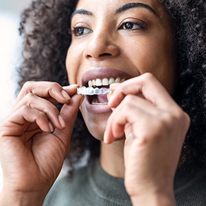 Woman inserting Invisalign over her top teeth