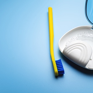 Yellow toothbrush next to clear aligner in carrying case